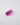 Angled side view of an elongated pink lab-grown sapphire on a pale background.