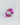Pink and green lab-grown sapphire tilted on a pale textured surface.