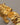 A close-up of a chunky, premium open-cuff bracelet featuring an irregular molten gold and crushed foil texture, made of real gold-plated brass, resting elegantly on a smooth grey background.-3