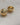 A close-up of two pairs of high-gloss dome stud earrings in gold and silver finishes, showing the smooth half-sphere front and the hollow-back construction with stud posts, resting on a textured cream fabric-7