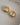 A close-up of a pair of thick, highly polished 18K gold-plated huggie hoop earrings featuring a smooth tapered design and a secure hinged snap closure, isolated on a white background.-6