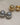 A close-up of two pairs of high-gloss dome stud earrings in gold and silver finishes, showing the smooth half-sphere front and the hollow-back construction with stud posts, resting on a textured cream fabric-2
