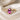 Concept image of an elongated pink sapphire ring with pale pink geometric side stones on cream fabric.