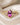 Concept image of an elongated pink sapphire ring with pale pink geometric side stones on cream fabric.